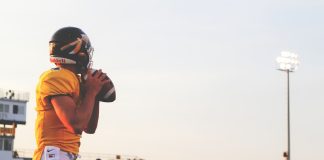man holding brown football ball