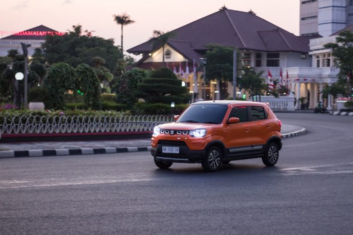 Photo by Indra Projects an orange truck driving down a street next to tall buildings
