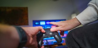Close-up of hands using a game controller in a cozy living room setting.