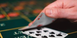 Close view of playing cards and hand on a casino table, capturing the gambling atmosphere.