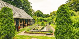 A lush green garden with a pond and house