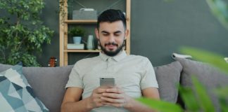 Man sitting on couch using smartphone