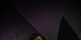 man in black long sleeve shirt holding black laptop computer