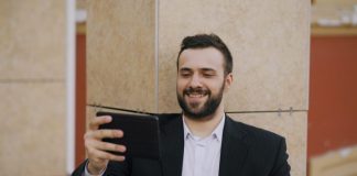 Man in suit smiling while looking at tablet