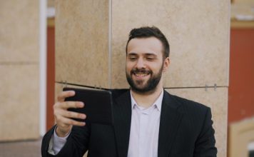 Man in suit smiling while looking at tablet