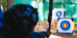 a woman is aiming a bow at a target