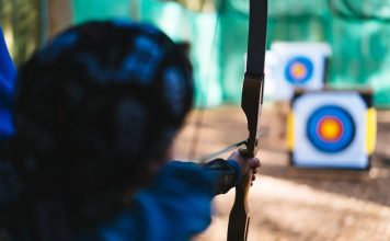 a woman is aiming a bow at a target