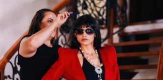 woman about to comb the hair of woman wearing red blazer