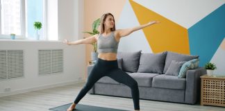 Woman practicing warrior ii pose on yoga mat.