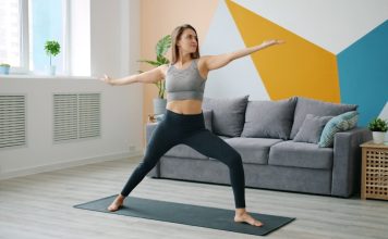 Woman practicing warrior ii pose on yoga mat.