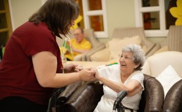 Caregiver assists elderly woman with walker.