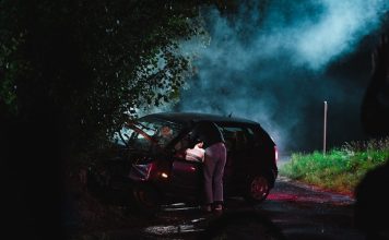 a person standing next to a car with smoke coming out of it