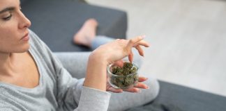 a woman sitting on a couch holding a bowl of marijuana
