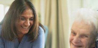 Nurse smiling with elderly patient in room