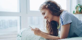 Young woman smiling while looking at her phone