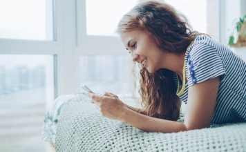 Young woman smiling while looking at her phone
