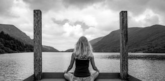 A woman sitting on a dock in front of a body of water