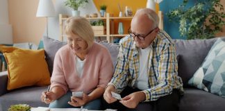 Elderly couple reviews finances at home on couch.
