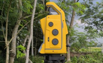 A yellow surveying instrument stands outdoors.