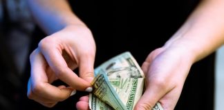 person holding fan of 100 us dollar bill