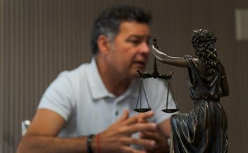 Why Injury Victims Rarely Pay Their Lawyer Anything Up Front A man sitting at a table in front of a statue