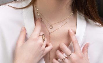 a close up of a person wearing rings and a necklace