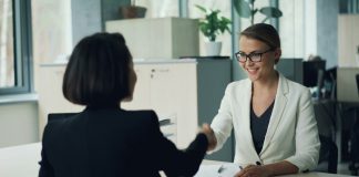 Two women shaking hands across a desk