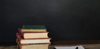 pile of books beside white printer paper and black ballpoint pen