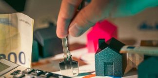 hand holding key over house models