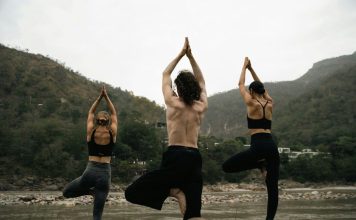 Five Healthy Habits That Can Help Replace Unhealthy Coping Mechanisms three people doing yoga on a rock near a river
