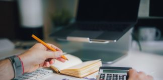 a person sitting at a desk with a calculator and a notebook
