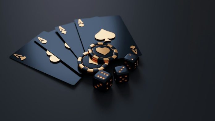 Black playing cards with gold aces, poker chips, and dice on dark surface