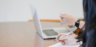 person holding pen writing on paper