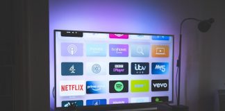 A television screen displaying a grid of streaming service app icons in a dim room