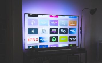 A television screen displaying a grid of streaming service app icons in a dim room