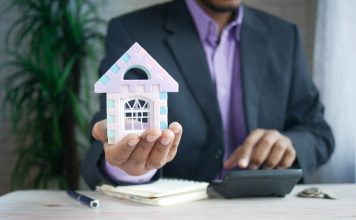 How to Read a Property Tax Rate Map Without Getting Fooled by the Colors man holding model house at desk with calculator
