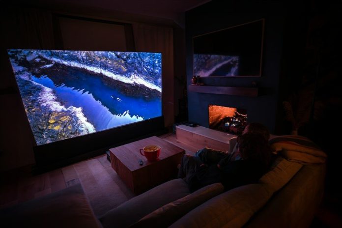 A person sitting on a couch in front of a flat screen TV