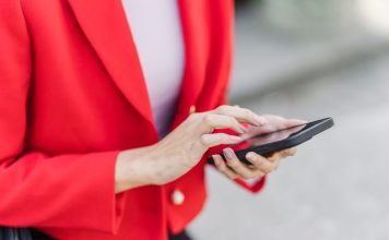 A woman in a red blazer using a smartphone, engaged in mobile technology.