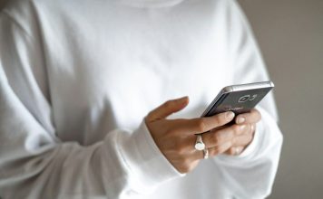 person in white long sleeve shirt holding black smartphone