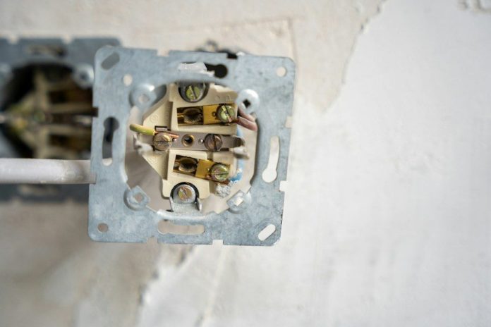 Electrical outlet disassembled, revealing the wiring