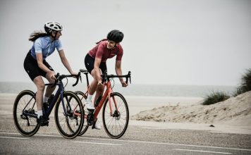 man and woman riding road bikes at the road near shore
